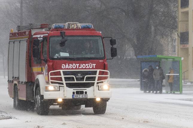 Tűzoltóautó és buszmegállóban várakozó utasok hóviharban Nyíregyházán