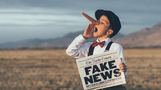 Fiú híreket kürtöl világgá, kezében Fake News feliratú újság