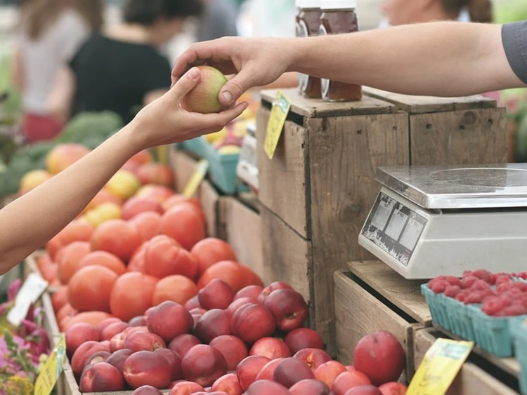 A termelői piacon a vásárló almát vesz. 