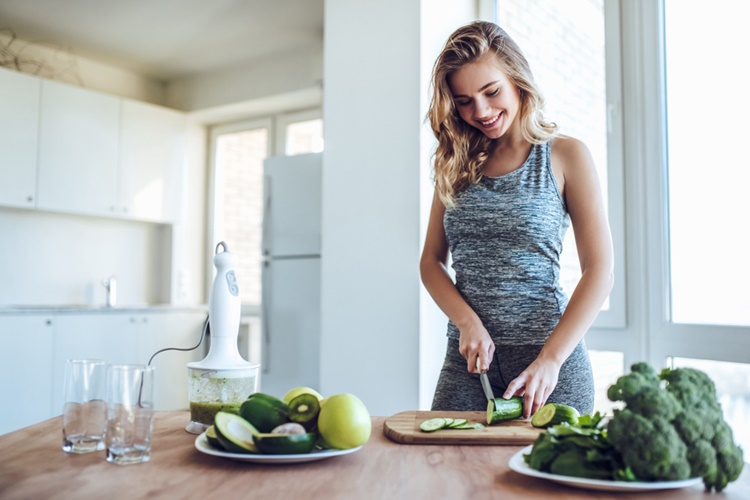 Nő konyhában zöldségeket vág, tudatos vásárló, biofogyasztó